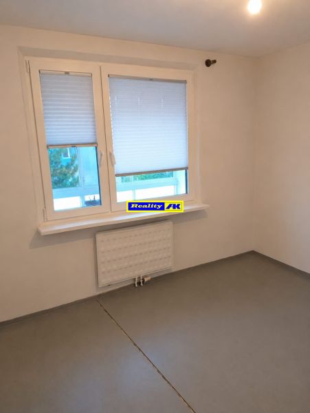Empty room with a gray floor and a window in a 3-room apartment.