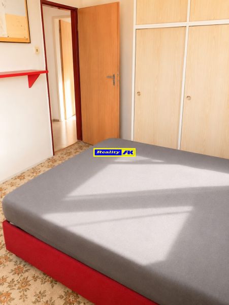 A room with a bed, a wardrobe, and a carpet in a 3-room apartment.