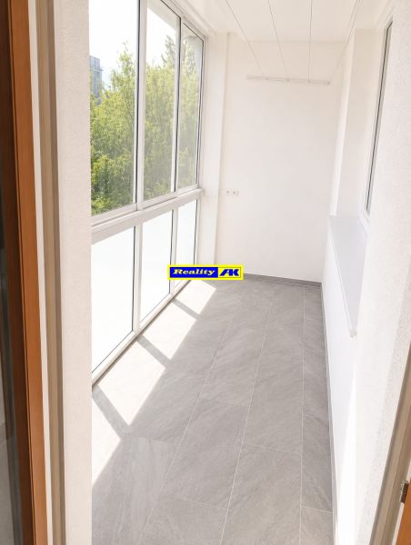 A glazed terrace in a 3-room apartment with tiles and a large window, brightening the space.