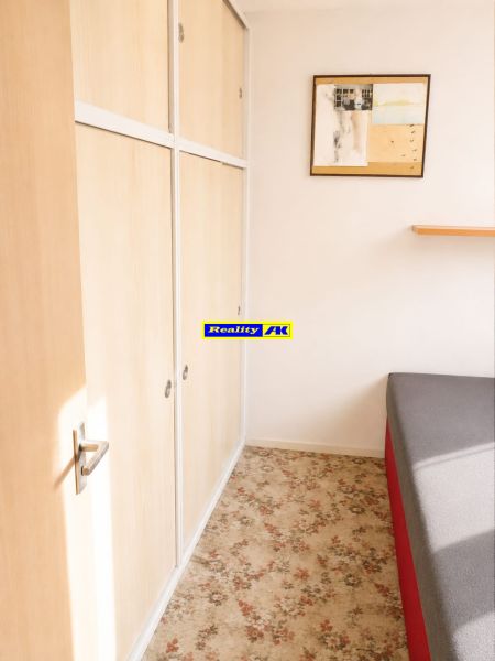 A bedroom in a 3-room apartment with a carpet and a wardrobe.