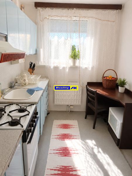 A kitchen in a 3-room apartment with a gas stove, dining table, and rug.