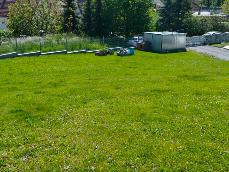 Grassy residential plots in Horná Ves with a garden house and trees in the background.