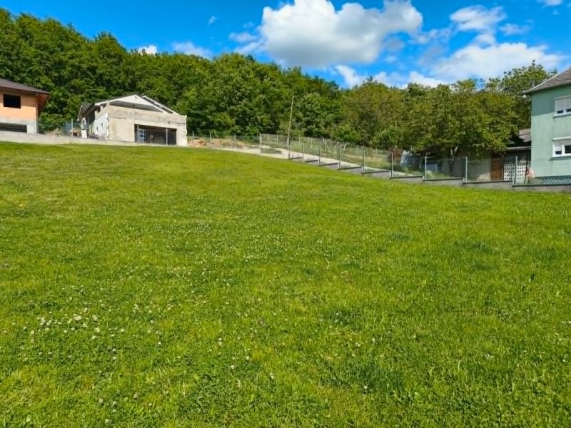 A green plot in Horná Ves for living, surrounded by houses and trees.