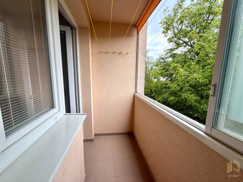 A balcony with glazing and a view of greenery in a 2-room apartment.