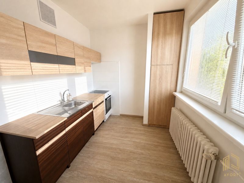 A kitchen in a 2-room apartment with wooden decor and large windows.