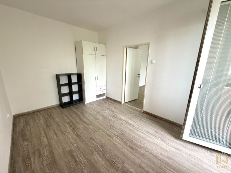 A room in a 2-room apartment with furniture and a wooden decor floor.