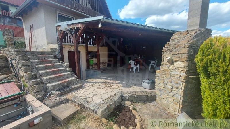 A cottage in Holíč with a covered terrace made of stone materials and plastic chairs.