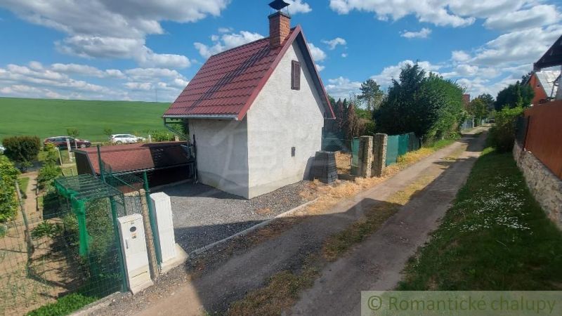 A cottage in Holíč with a slanted roof, an adjacent road, and open countryside.