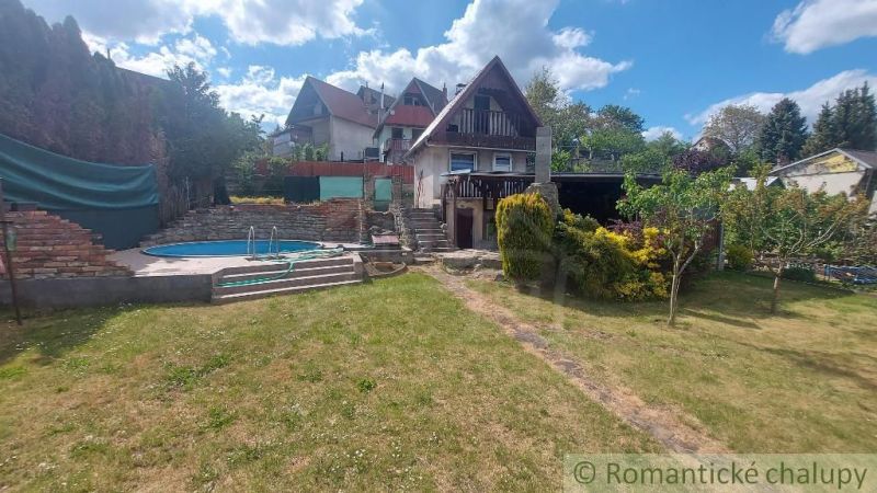 A cottage in Holíč with a pool and a garden surrounded by green vegetation.