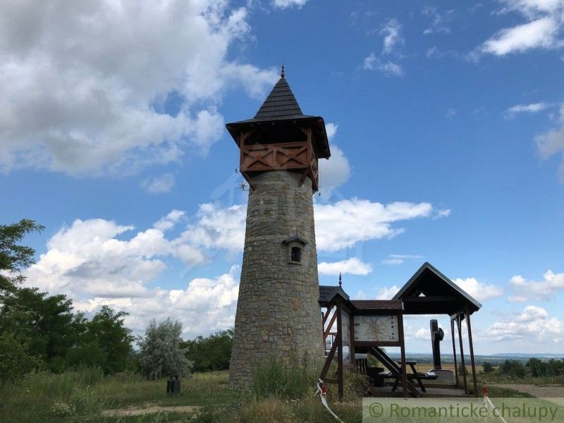 Stone lookout tower near the cottage in Holíč with a wooden roof and an information panel.