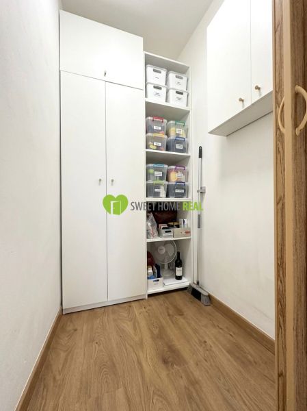 Storage space with white cabinets and shelves, wooden decor flooring in a 3-room apartment.