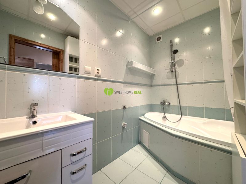 A bathroom in a 3-room apartment with a shower and a bathtub, tiled with light tiles.