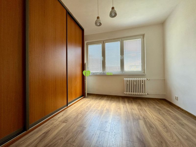 A room in a three-room apartment with a wooden decor floor and a built-in wardrobe.