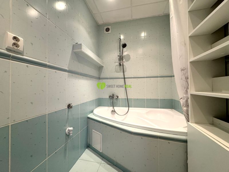 A bathroom with a bathtub and storage shelves in a 3-room apartment.