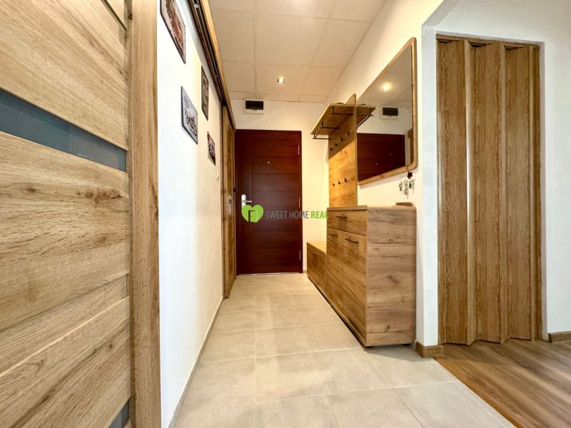 A hallway with a wooden decor floor in a 3-room apartment.