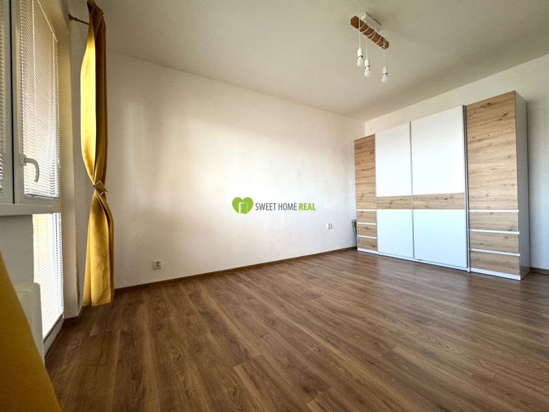 A room in a 3-room apartment with a wooden decor floor and a large wardrobe.