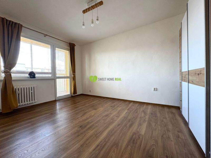 Living room with wood-patterned flooring, white walls, and a large window in a 3-room apartment.