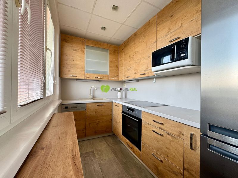 A kitchen in a 3-room apartment with a wooden decor floor and modern equipment.