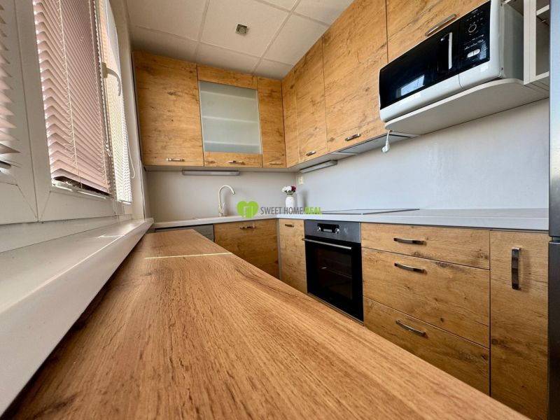A kitchen in a 3-room apartment with wooden decor and appliances.