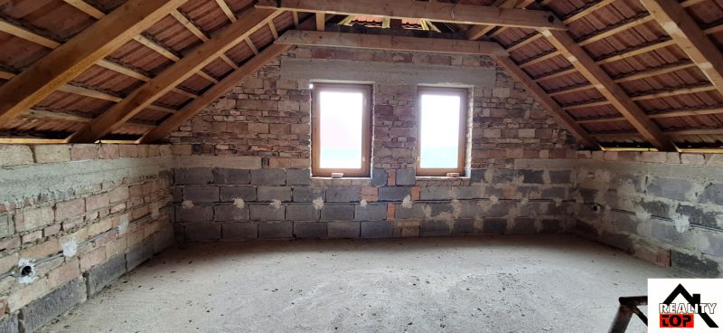 The attic of a family house with a brick wall and two windows.
