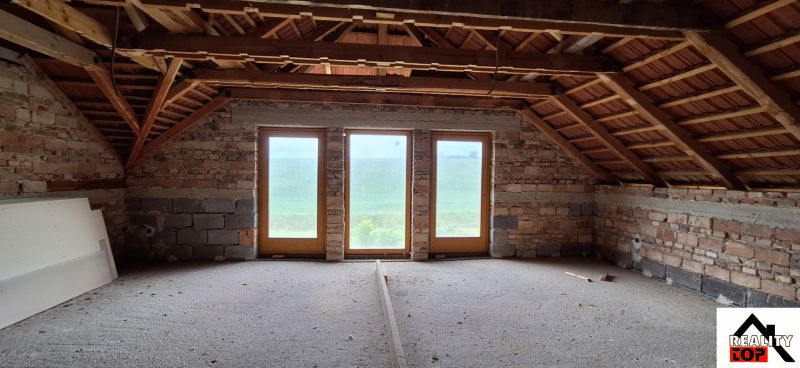 The attic of a family house with wooden beams and large glass doors.