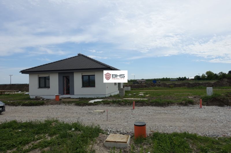 A family house in Reca, simple structure with grassy surroundings and a gravel access road.