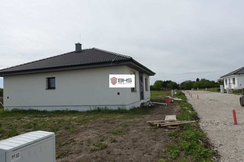A family house in the town of Reca with a sloped roof, undeveloped surroundings, and a gravel road.