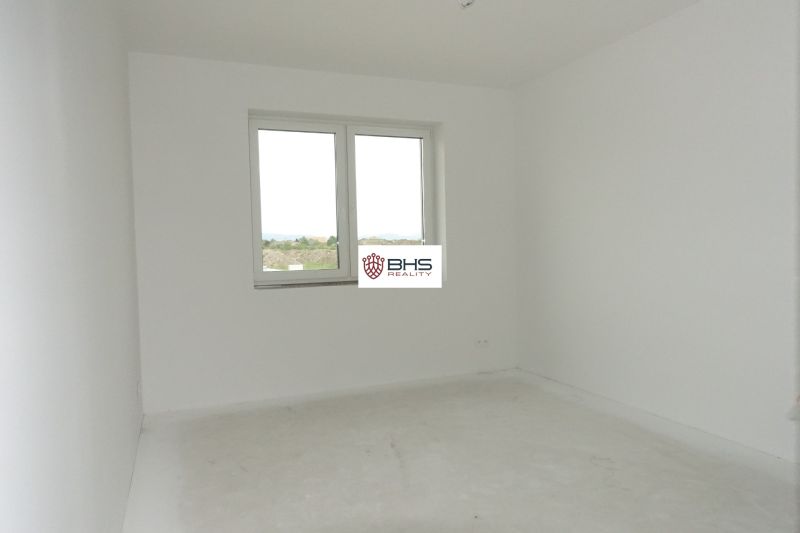 An empty room in a family house with white walls and a window.