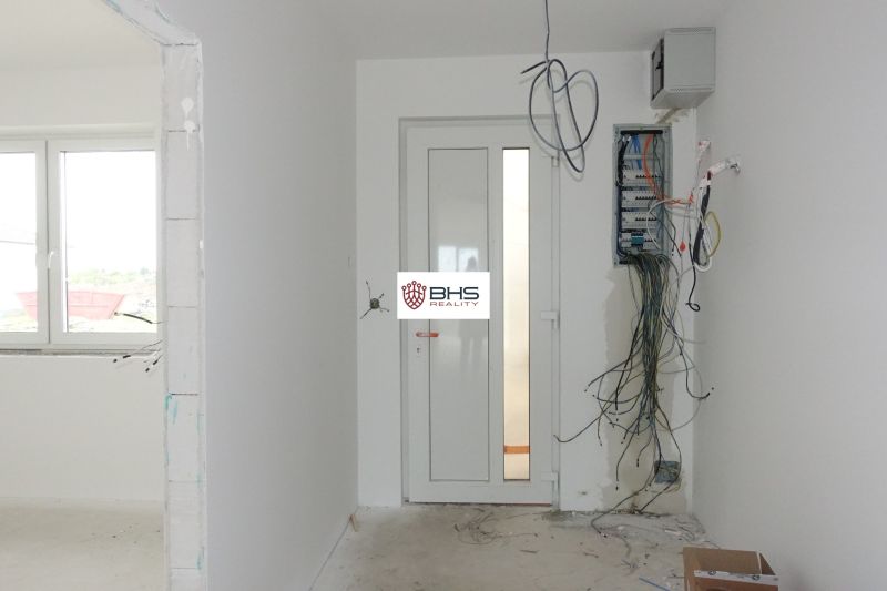 In the family house, there is unfinished electrical wiring with hanging cables and a fuse box.