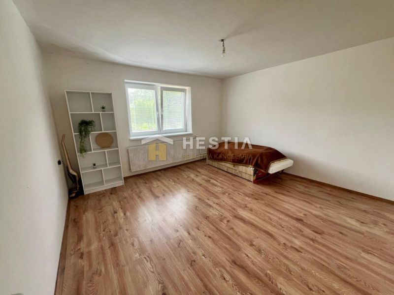 Room in a family house with a bed, shelf, and floor with wooden decor.