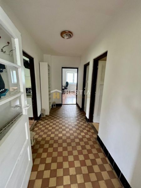 A hallway in a family house with checkered flooring and white walls.