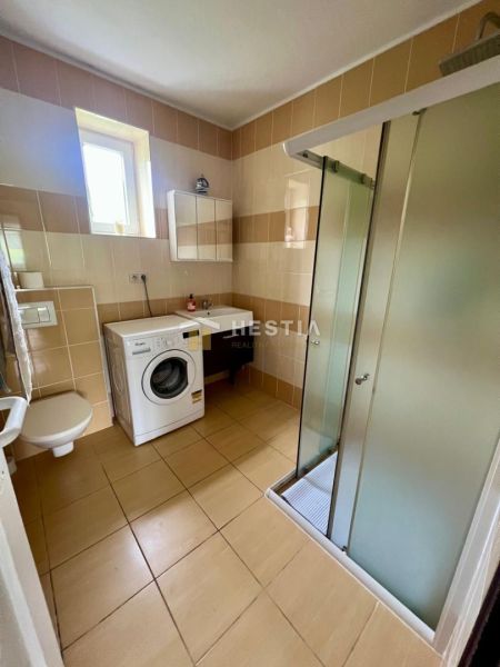 Bathroom in a family house with a washing machine, shower, and toilet.