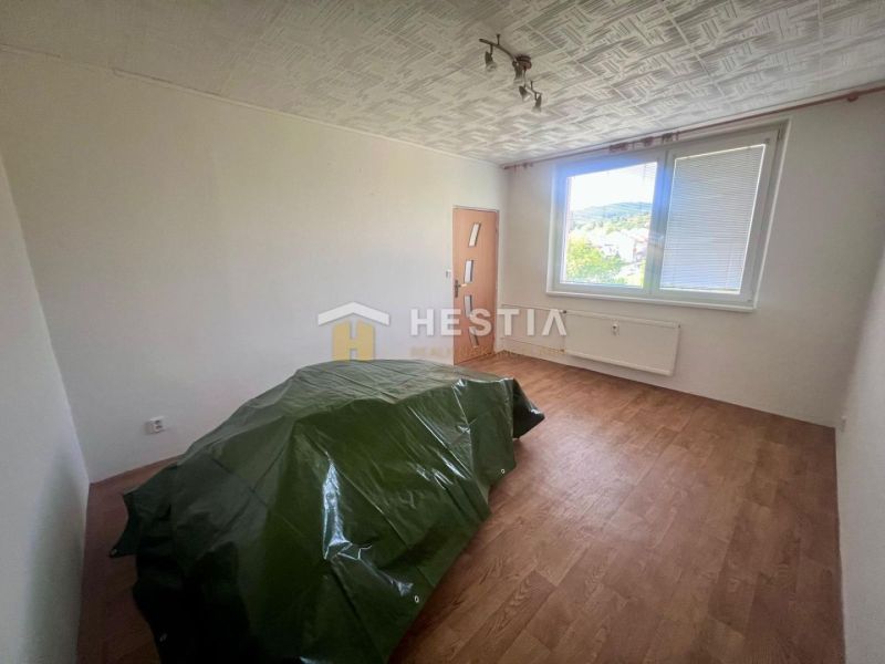 A room in a three-room apartment with a wooden decor floor and a green sheet.