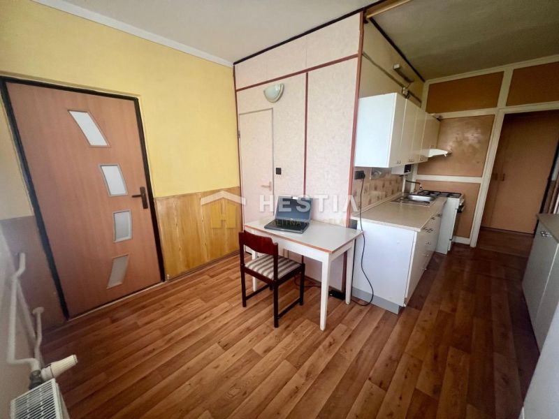 A kitchen in a 3-room apartment with a wooden decor floor and light furniture.