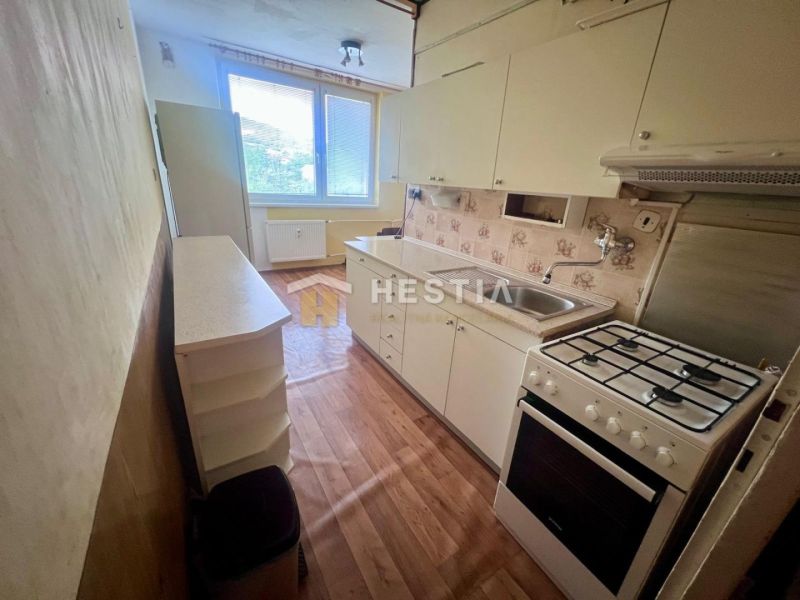 A kitchen in a 3-room apartment with a wooden decor floor and a gas stove.