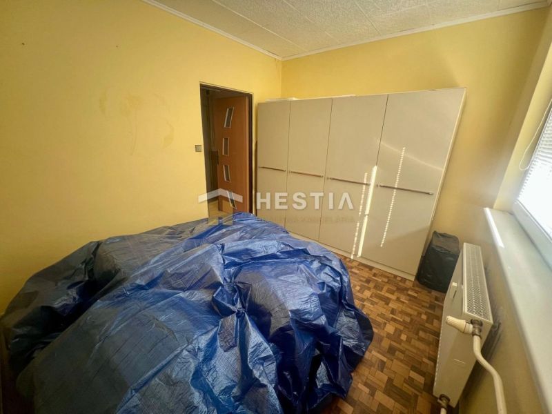 A room in a 3-room apartment with a wooden decor floor and simple furnishings.