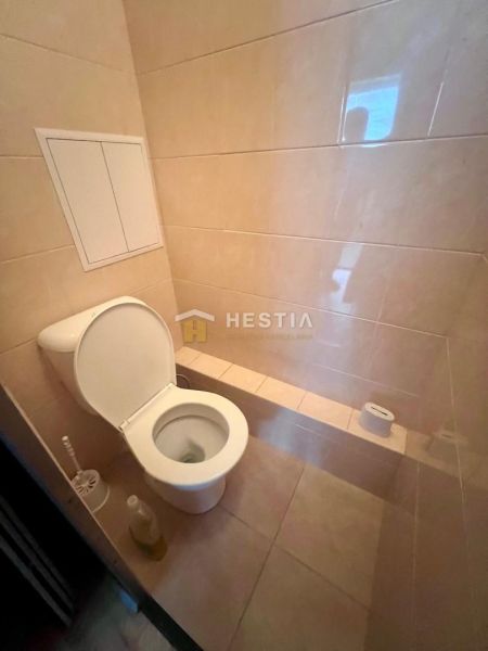 A bathroom with a toilet in a 3-room apartment with predominantly beige tiles.