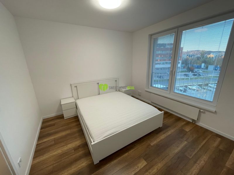 A bedroom in a 2-room apartment with a bed and a wooden decor floor.