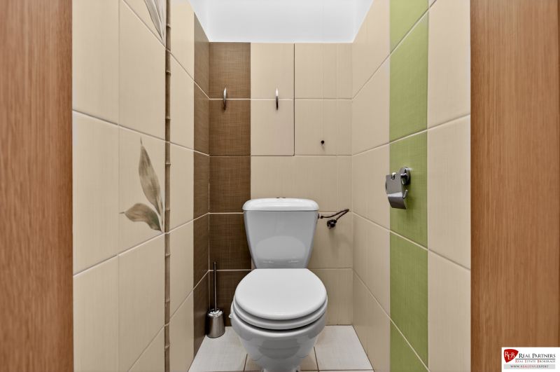 A toilet with tiles in a 3-room apartment, with ceramic tiles and toilet paper.