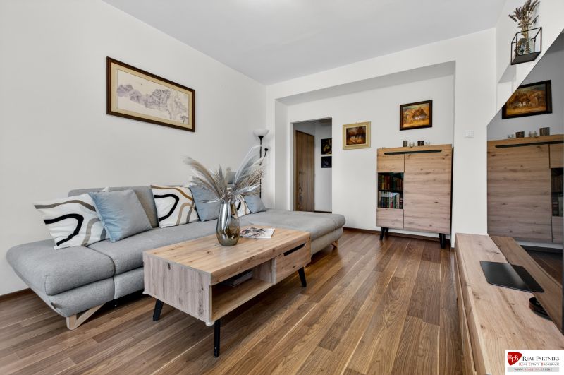 Living room in a 3-room apartment with a gray sofa and a floor with a wooden decor.