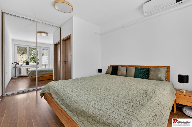 A bedroom in a 3-room apartment with a bed, a wardrobe, and a floor with a wooden decor.