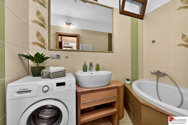 Bathroom with a washing machine, sink, and bathtub in a 3-room apartment. Walls with decorative tiles.