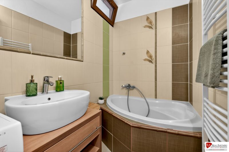 Bathroom with a corner bathtub and a sink in a 3-room apartment, beige tiles.
