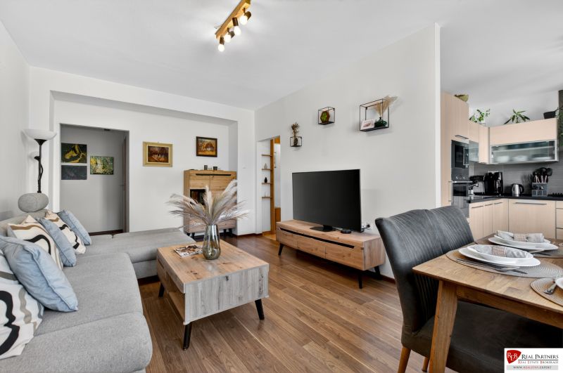 Living room in a three-room apartment with a wooden decor floor, beautiful furniture, and a dining area.