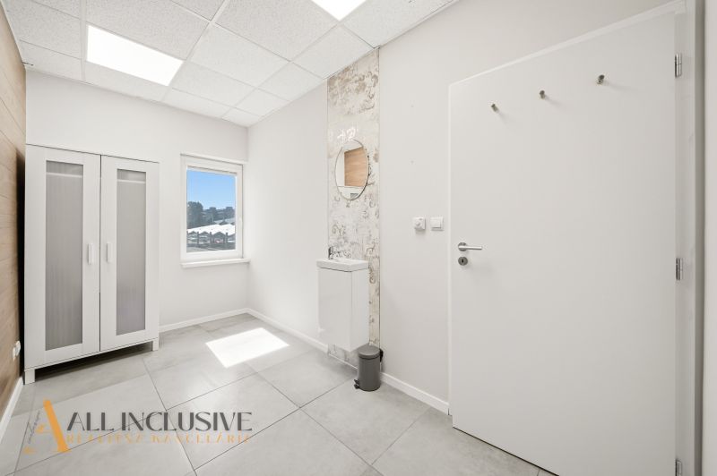 Interior of commercial premises with a white wardrobe, a mirror, and a tiled floor.