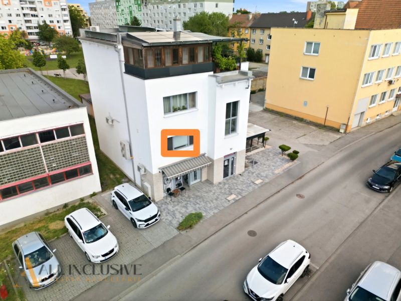 A building with commercial spaces on Obrancov mieru street in Galanta, with cars parked in front of it.