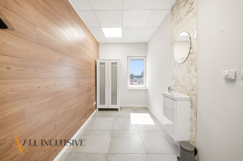 Interior of a commercial space with wood-patterned flooring, a sink, and a cabinet.