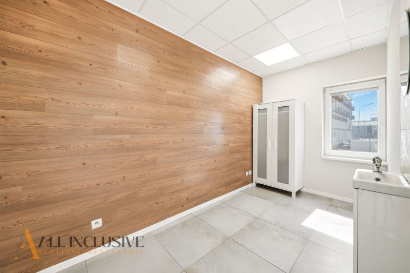 Interior of a commercial space with a decorative wall and a cabinet, floor with wooden decor.