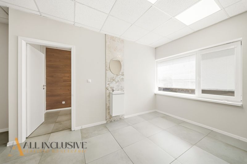 Interior of commercial spaces with white walls, tiles, and a large window.