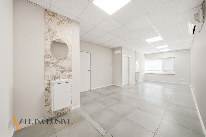 Commercial premises with ceramic flooring, light-colored walls, and a sink with a round mirror.